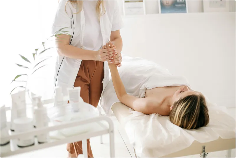 Masajista masajeando las manos de mujer en una cama